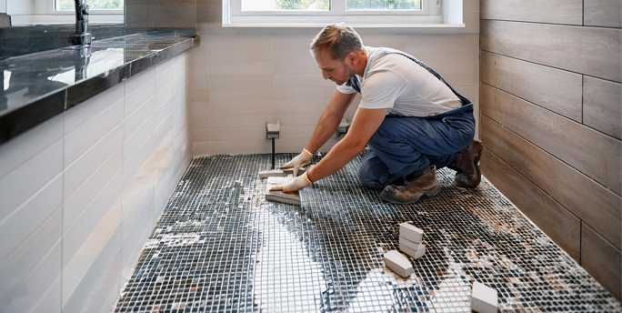 SGM-Handwerker verlegt sorgfältig Mosaikfliesen in einem eleganten Badezimmer, um perfekte Ergebnisse zu erzielen.