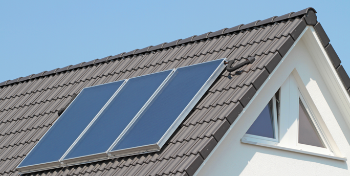 Techniker installiert eine Solarthermie-Anlage auf einem Dach.